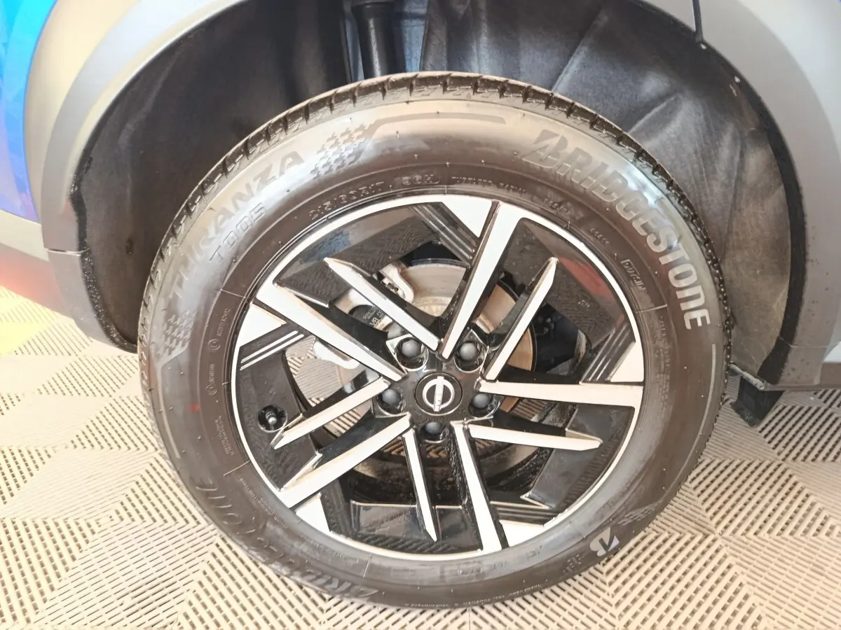 Gros plan sur la roue avant gauche du Nissan Juke bleu, avec jante alliage noire et argentée au design moderne.
