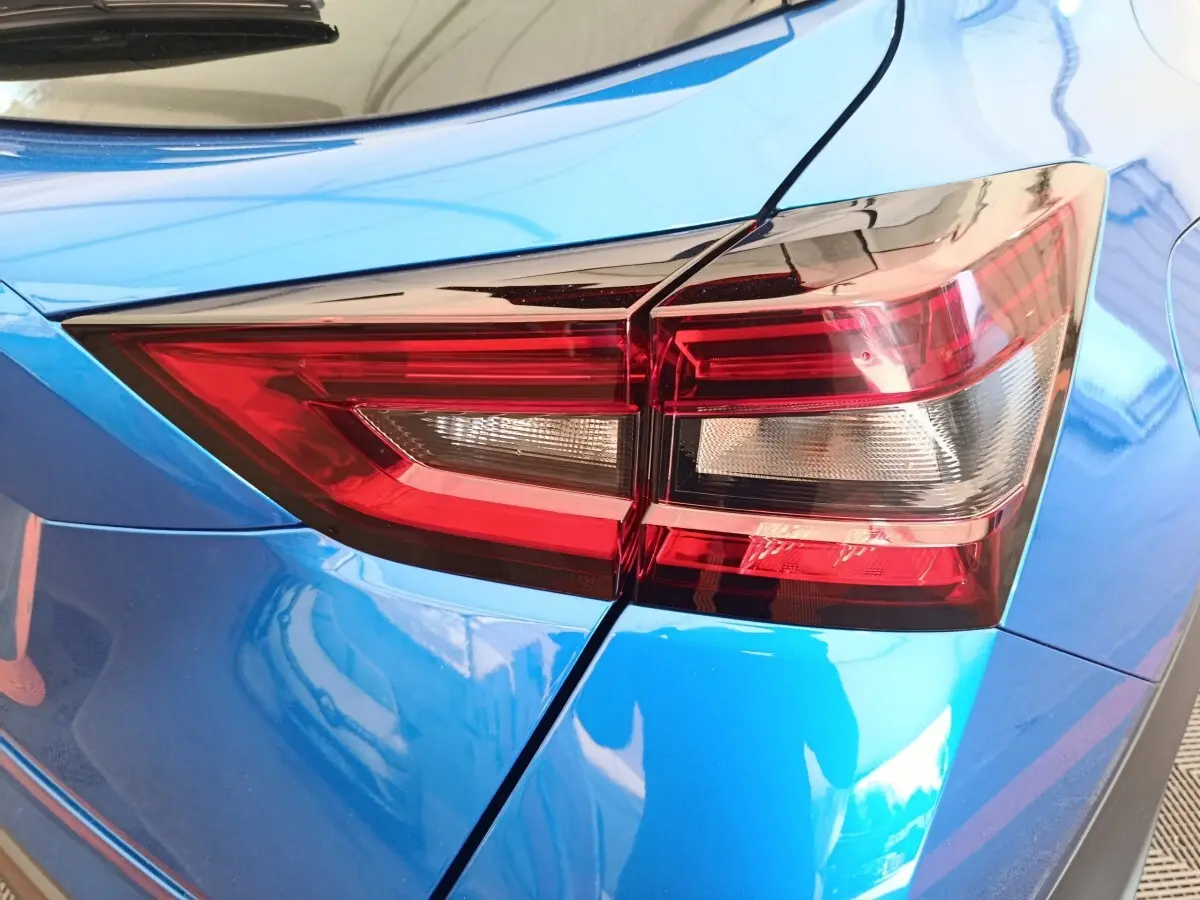 Gros plan sur le feu arrière droit rouge du Nissan Juke bleu 2025, soulignant la carrosserie brillante.
