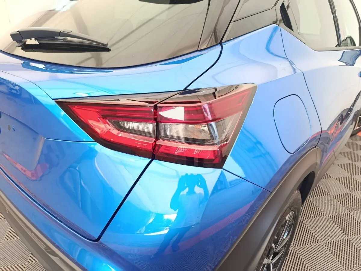 Vue 3/4 arrière droite du Nissan Juke bleu mettant en valeur le feu arrière et la trappe à carburant.