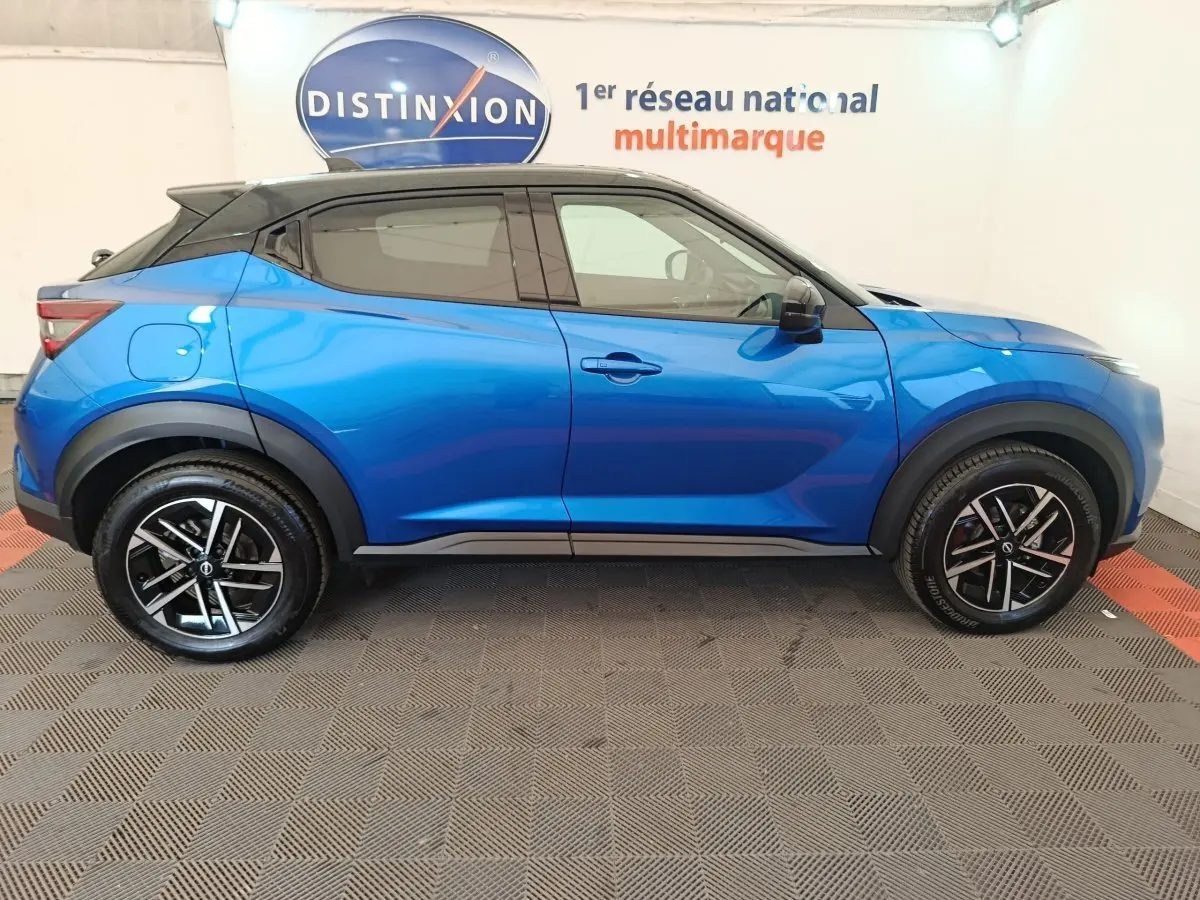 Profil droit d'un Nissan Juke bleu 2025 avec toit noir, jantes alliage noires et détails sportifs visibles.