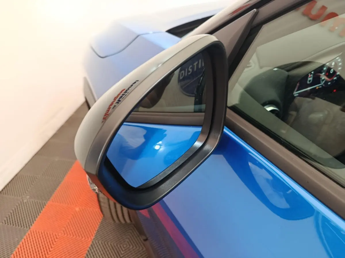 Rétroviseur côté gauche en gros plan sur Nissan Juke bleu, avec partie avant et tableau de bord visible.