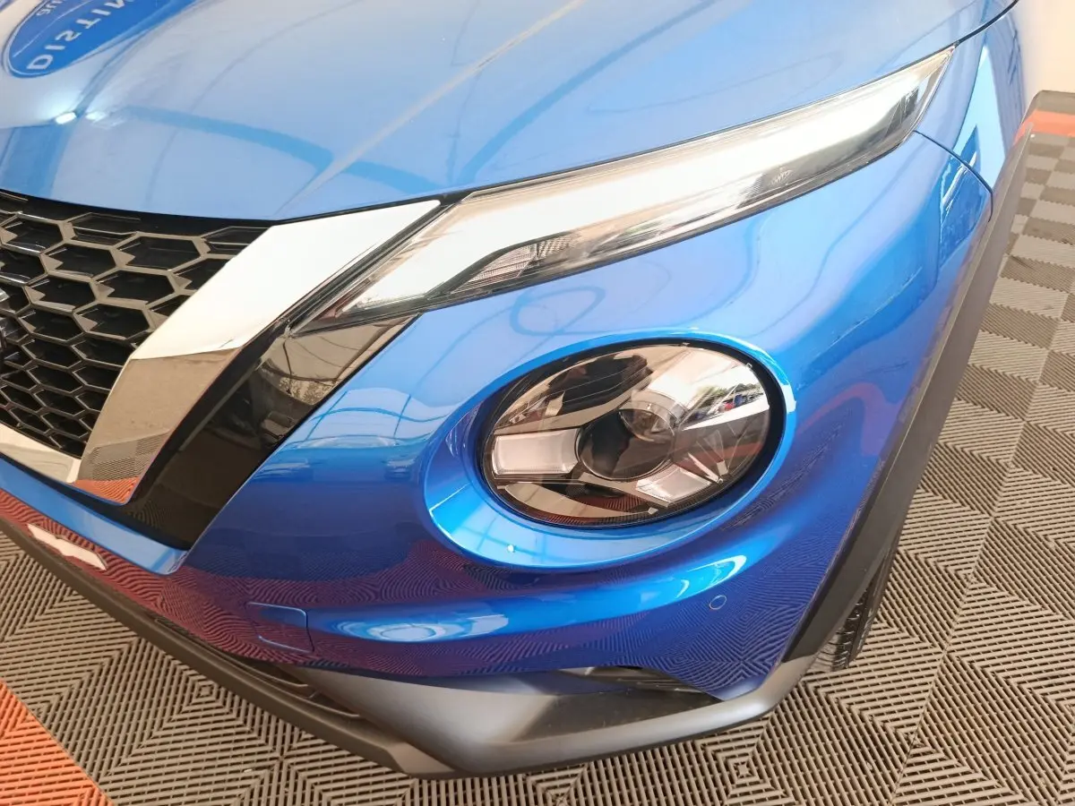 Gros plan sur l'avant droit bleu vif du Nissan Juke 2025, mettant en valeur ses phares LED distinctifs et la calandre noire.
