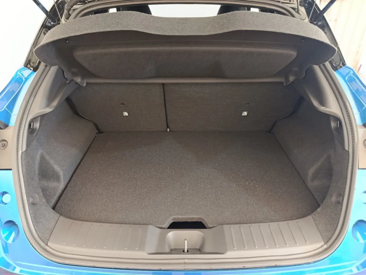 Coffre ouvert vu de l'arrière d'un Nissan Juke bleu 2025, montrant l'espace de chargement vide et la garniture intérieure grise.
