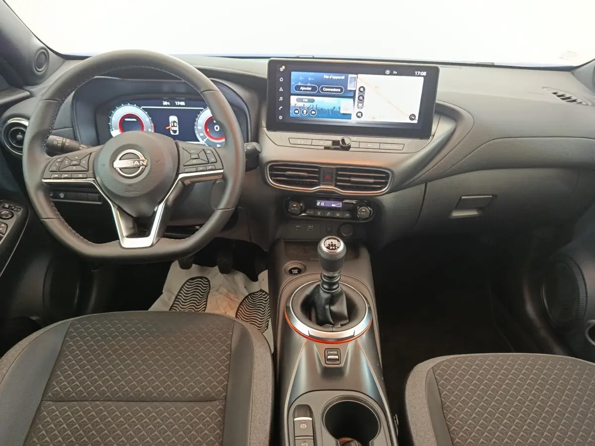 Vue intérieure du tableau de bord et volant du Nissan Juke 2025, avec écran tactile et levier de vitesses manuel.