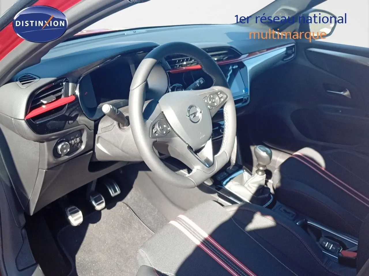 Intérieur de l’Opel Corsa 2023 vu côté conducteur, volant multifonction, sellerie noire avec surpiqûres rouges.