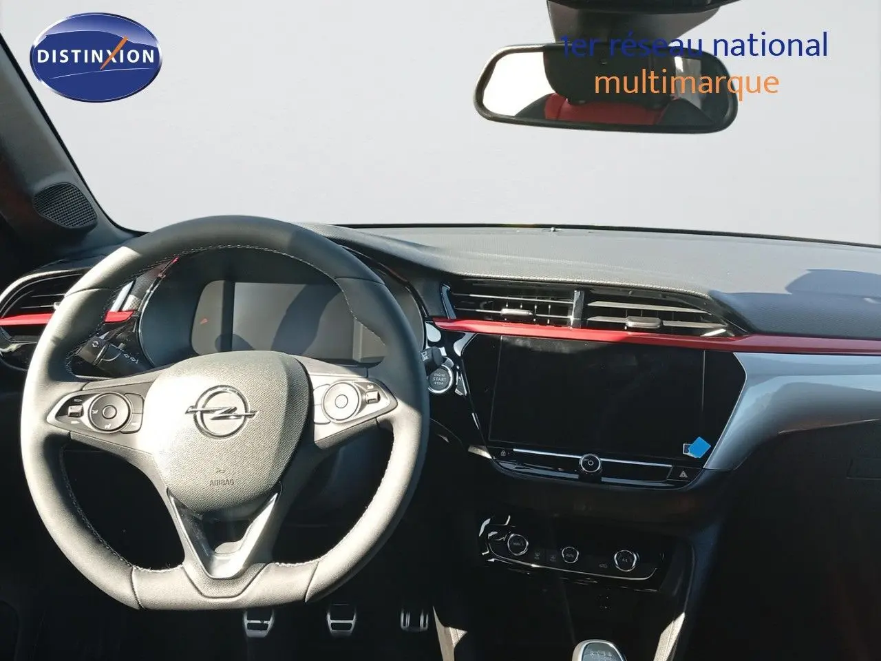 Vue intérieure du poste de conduite de l'Opel Corsa 2023, volant cuir noir et tableau de bord avec insert rouge Kardio Metal.