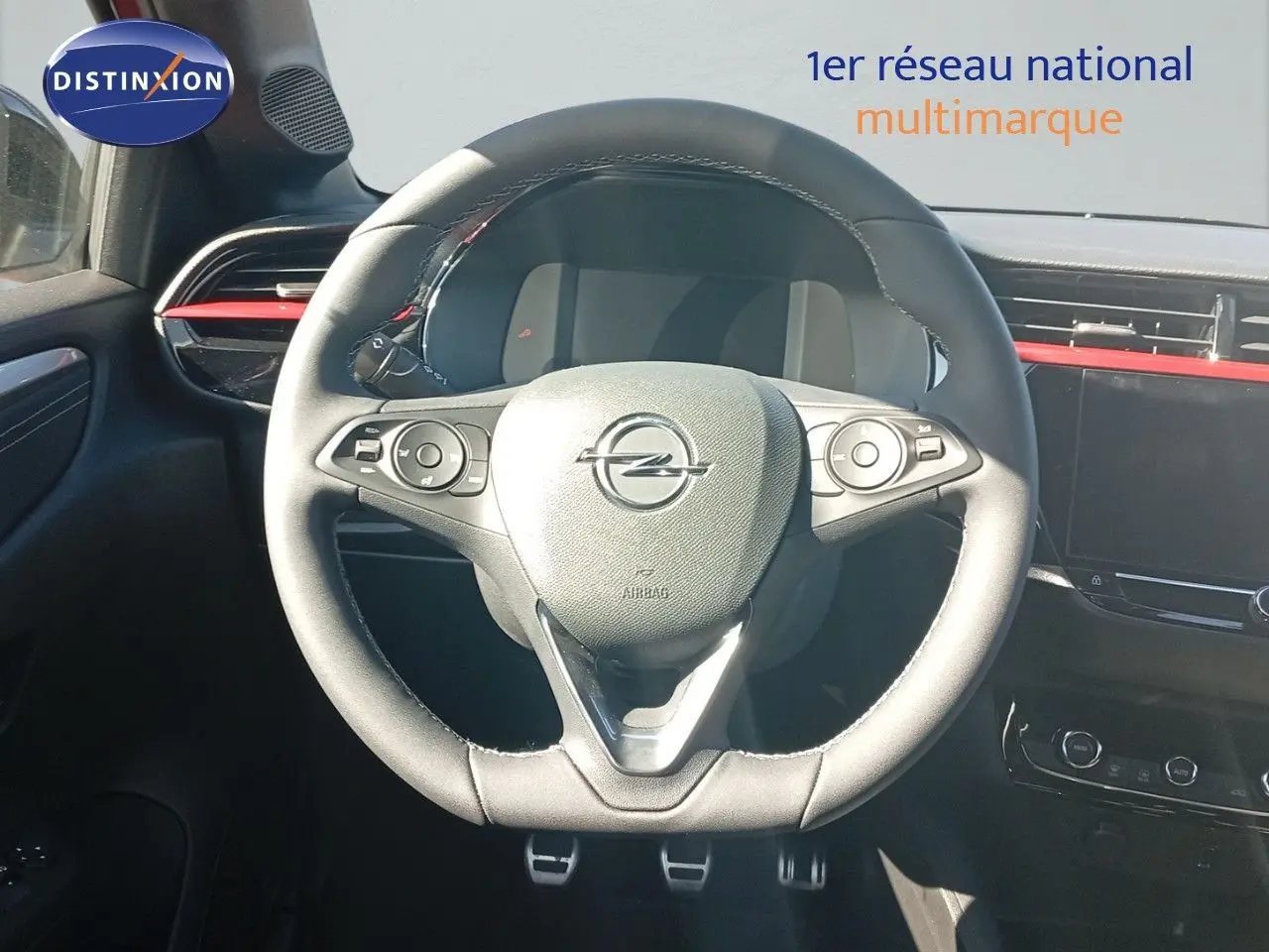 Vue centrée sur le volant noir de l’Opel Corsa 2023, avec tableau de bord et détails rouges en arrière-plan.