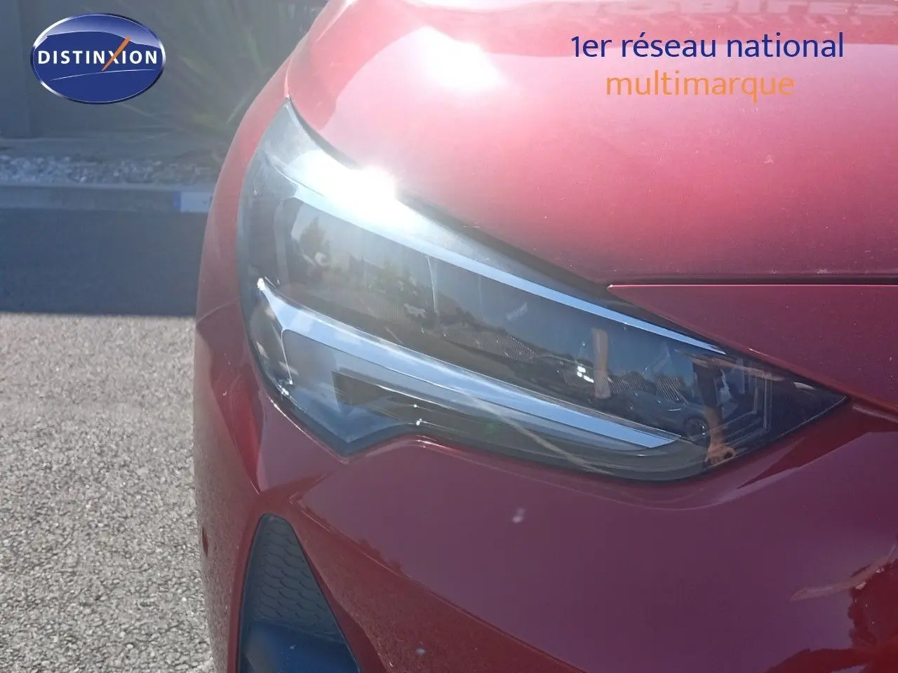 Gros plan sur le phare avant gauche de l’Opel Corsa rouge Kardio Metal avec toit noir, lumière LED brillante.