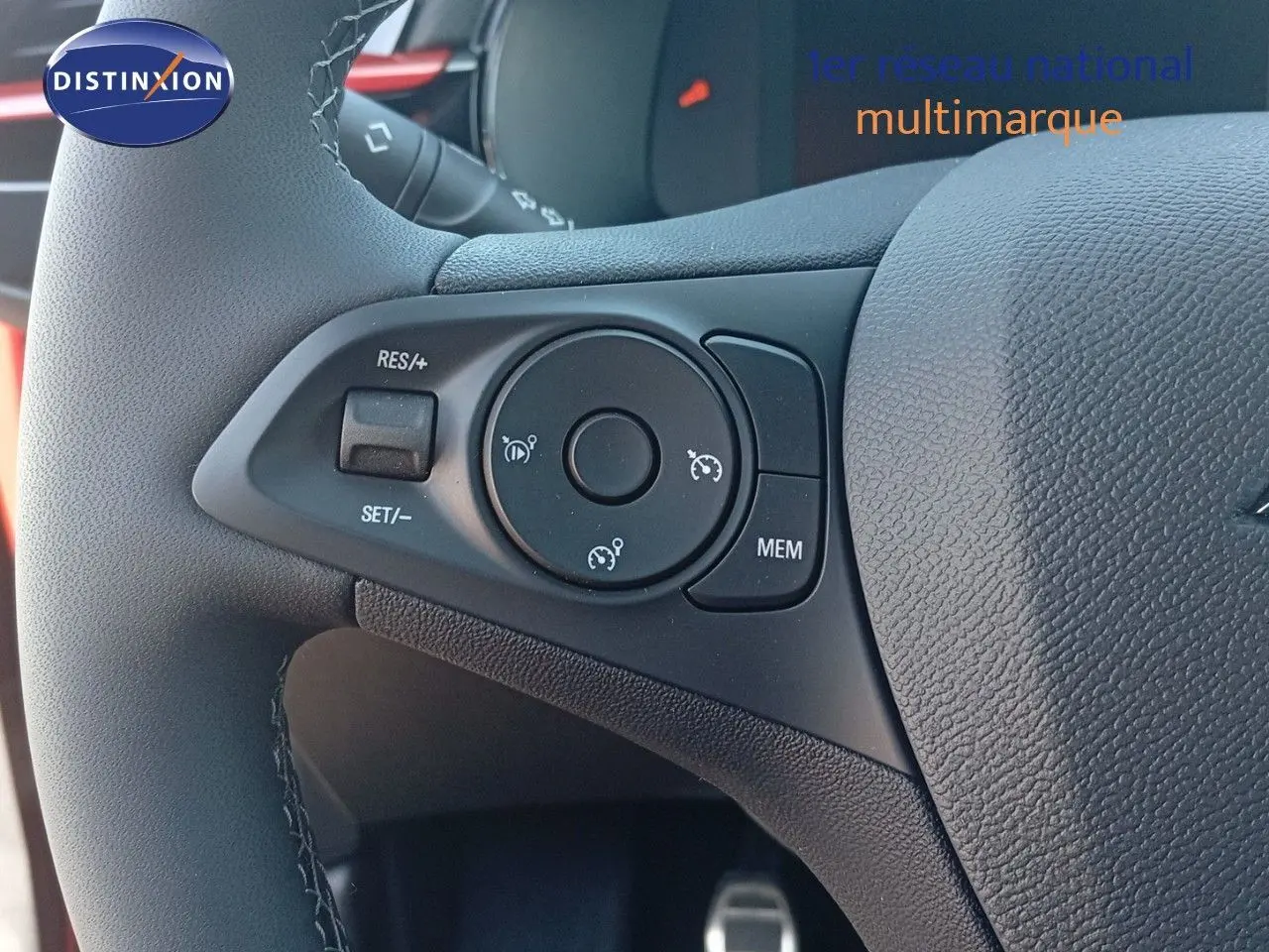 Gros plan sur les commandes au volant de l’Opel Corsa 2023, avec cuir noir et détails rouges visibles en arrière-plan.