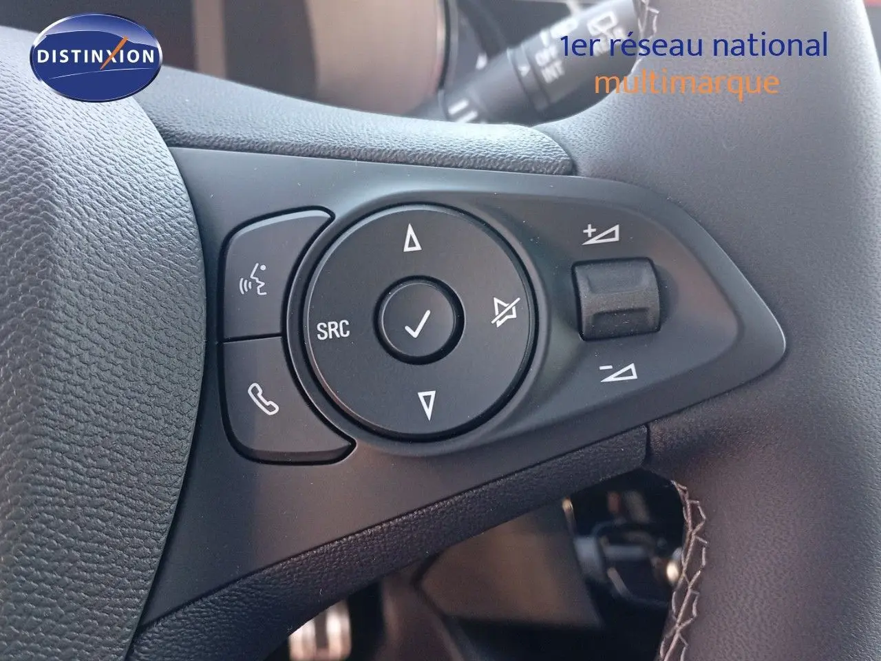 Gros plan sur les commandes multifonctions noires à gauche du volant d’une Opel Corsa 2023.