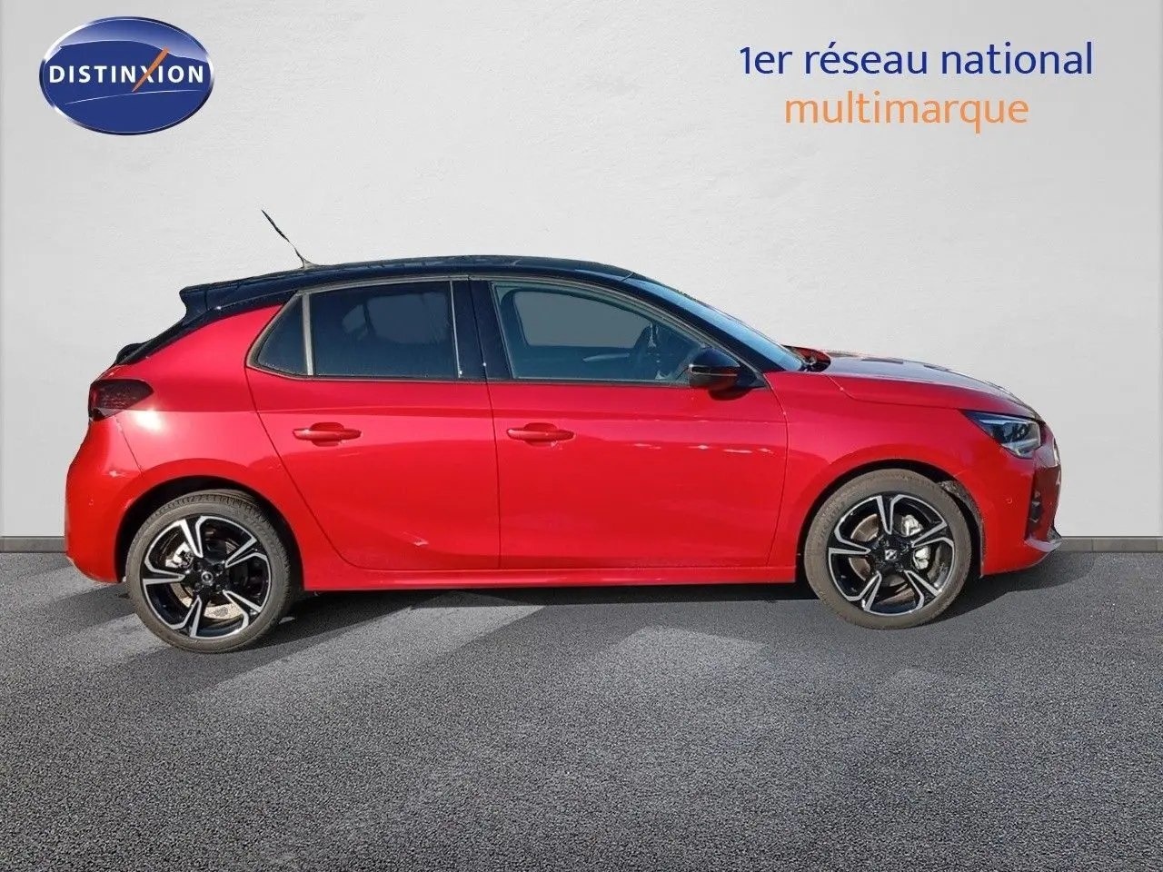 Vue de profil côté gauche d'une Opel Corsa 2023 rouge Kardio métal avec toit noir et jantes biton.