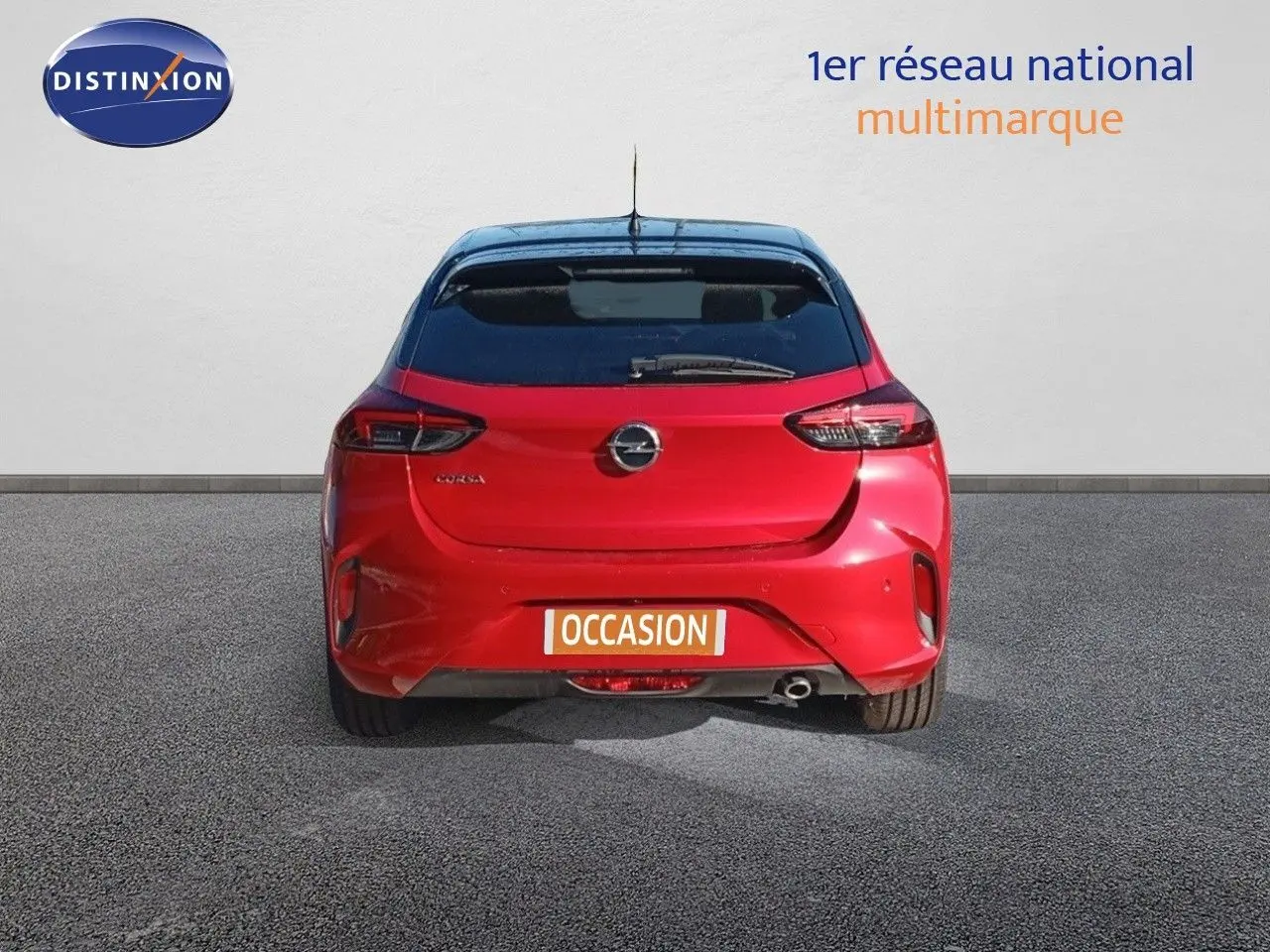 Vue arrière d'une Opel Corsa rouge Kardio métal avec toit noir, affichant la plaque "OCCASION" sur un sol gris.