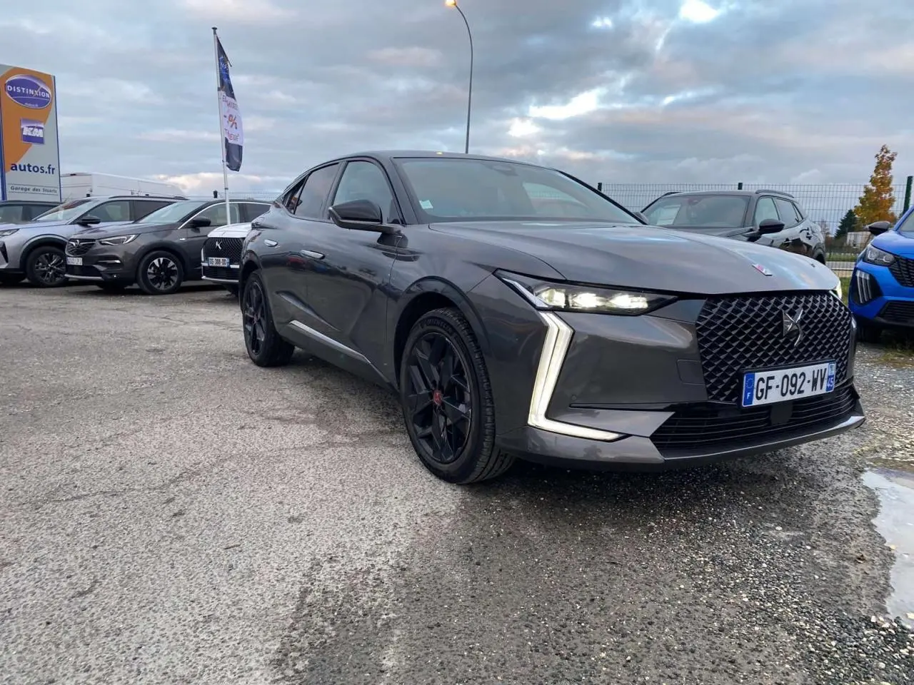 DS4 gris platinium vue 3/4 avant droit, avec calandre distinctive et feux LED en forme de flèche.