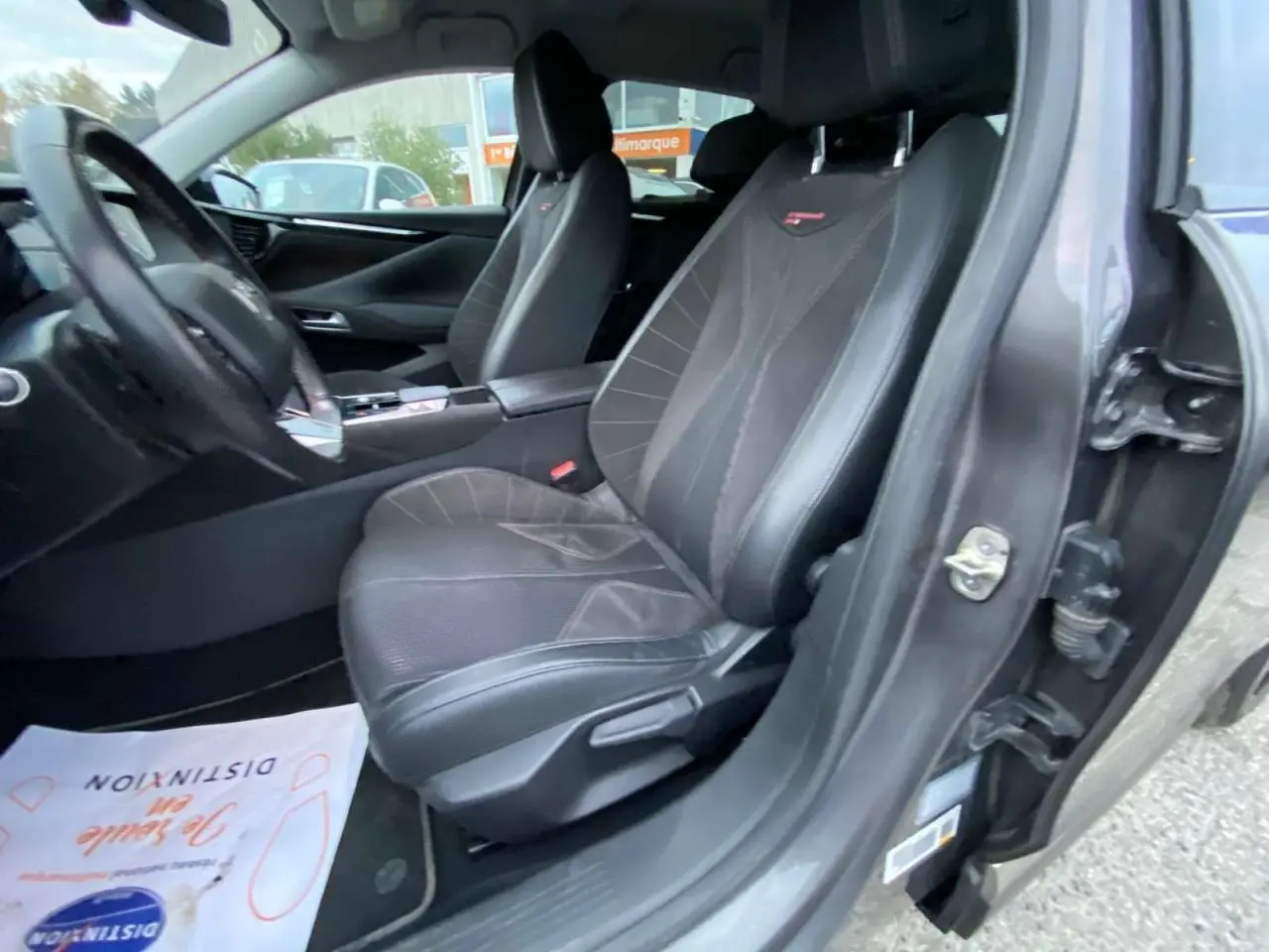 Vue intérieure côté conducteur du DS4 2022 gris platinium, mettant en valeur les sièges sport en cuir noir avec surpiqûres rouges.