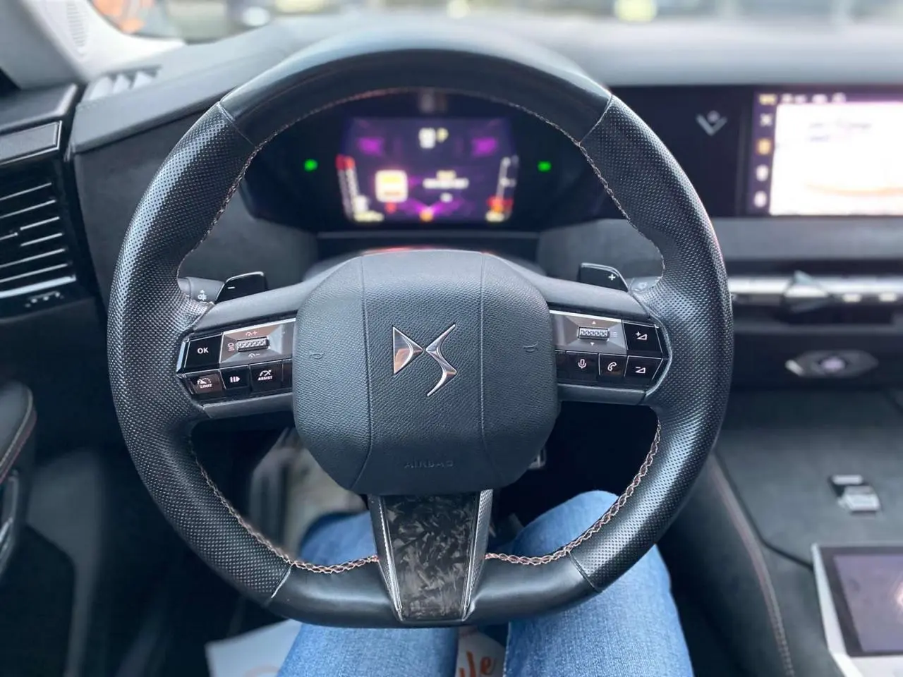 Volant en cuir noir avec logo DS au centre, tableau de bord numérique et écran tactile dans l'habitacle du DS4 gris platinium 2022.