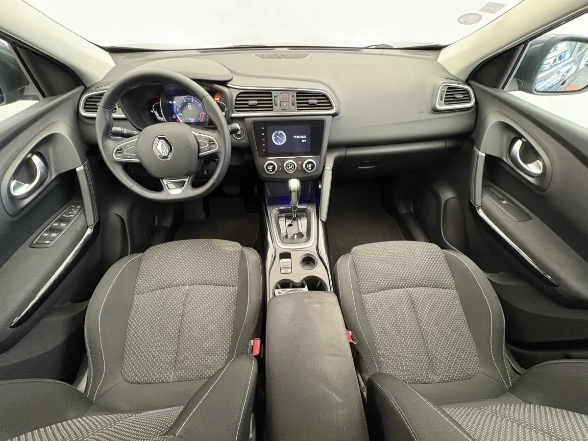 Vue intérieure avant du Renault Kadjar Intens 2019, tableau de bord noir avec écran tactile central et sièges tissu gris.