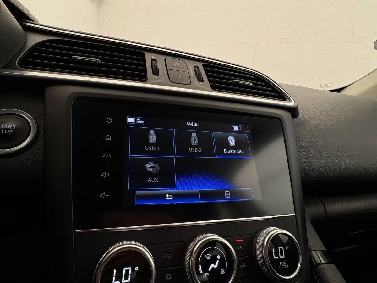 Vue rapprochée de l’écran tactile multimédia et des commandes de climatisation du tableau de bord du Renault Kadjar gris foncé.