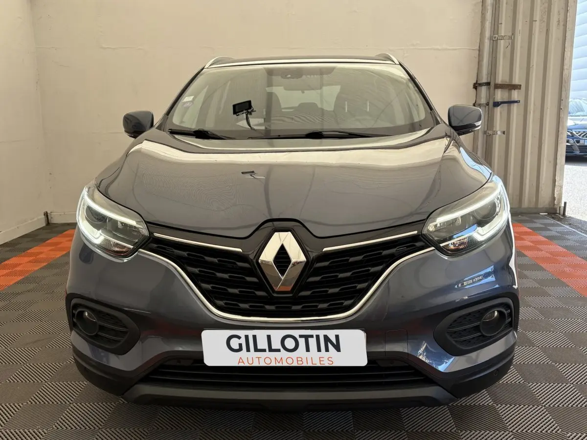 Vue avant d'un Renault Kadjar Intens gris foncé avec phares LED allumés dans un showroom.