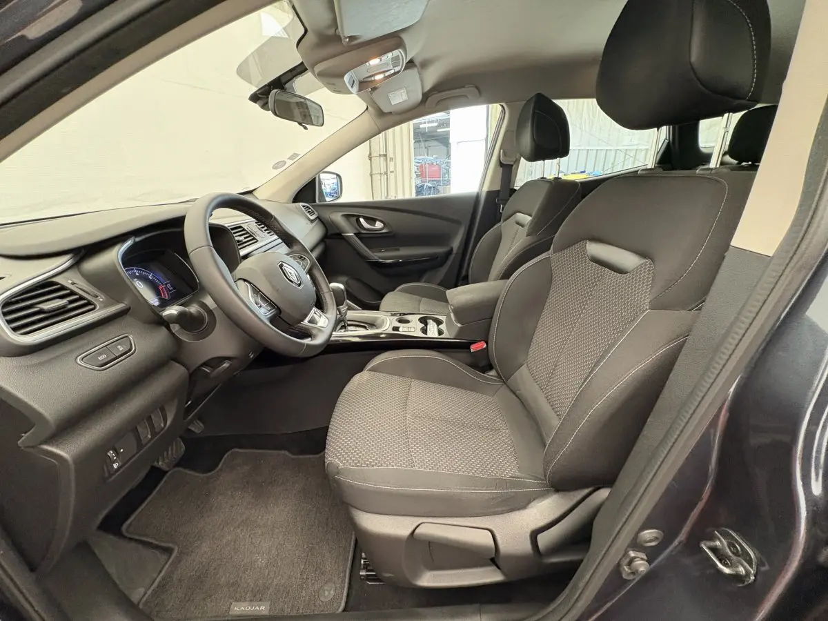 Vue intérieure côté conducteur du Renault Kadjar gris foncé 2019, sièges tissu noir et tableau de bord moderne.