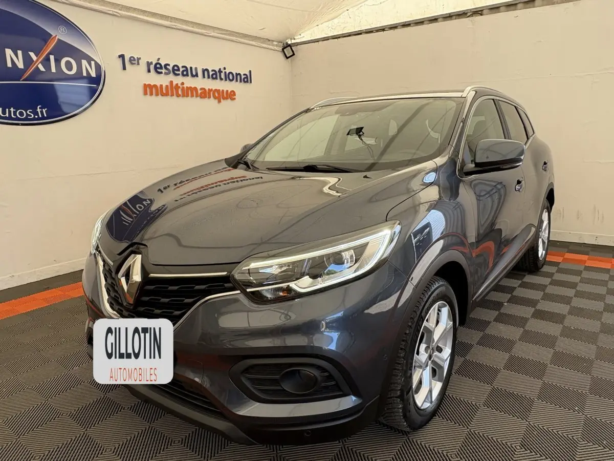 Renault Kadjar Intens gris foncé en 3/4 avant droit, avec phares LED et jantes alliage visibles en intérieur showroom.