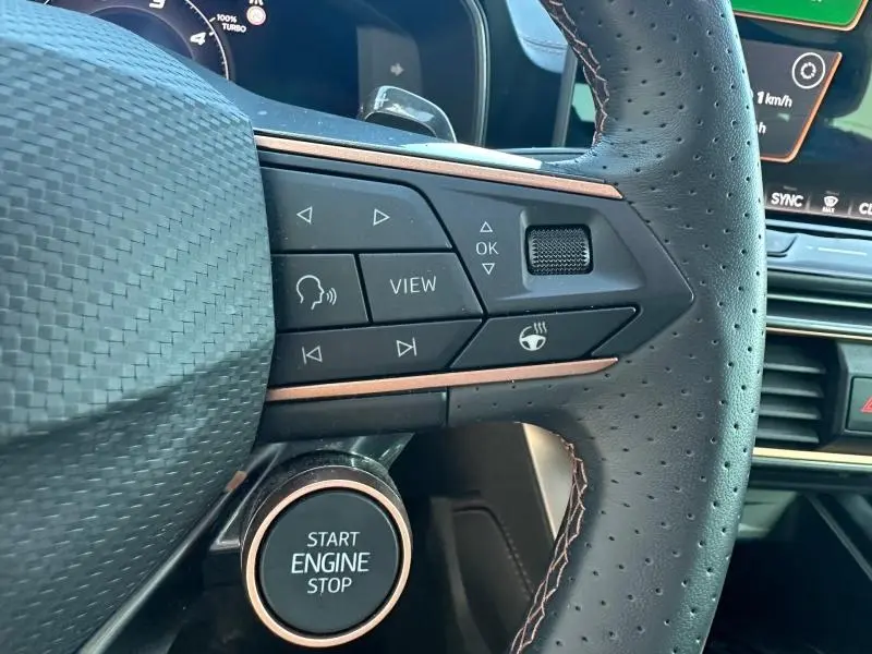 Gros plan sur le volant en cuir perforé et les commandes multifonctions du CUPRA Formentor blanc Nevada, avec bouton start/stop visible.