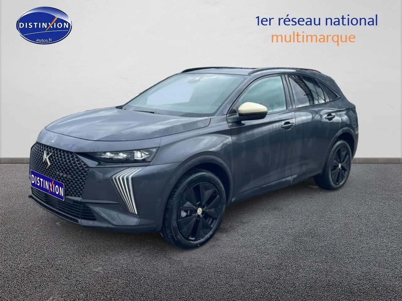 DS7 gris titane en 3/4 avant droit, avec calandre distinctive et jantes noires brillantes.