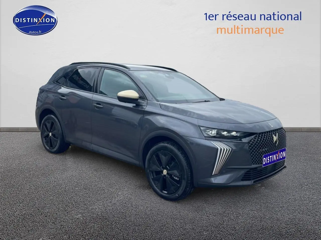 DS7 gris titane en 3/4 avant droit avec jantes noires et rétroviseurs couleur crème visible sur fond neutre.