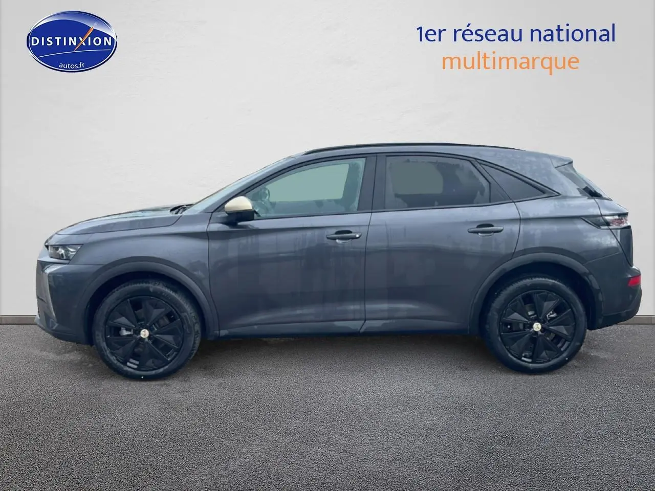 Vue de profil côté gauche d'un DS7 gris titane avec jantes noires et rétroviseur droit beige.