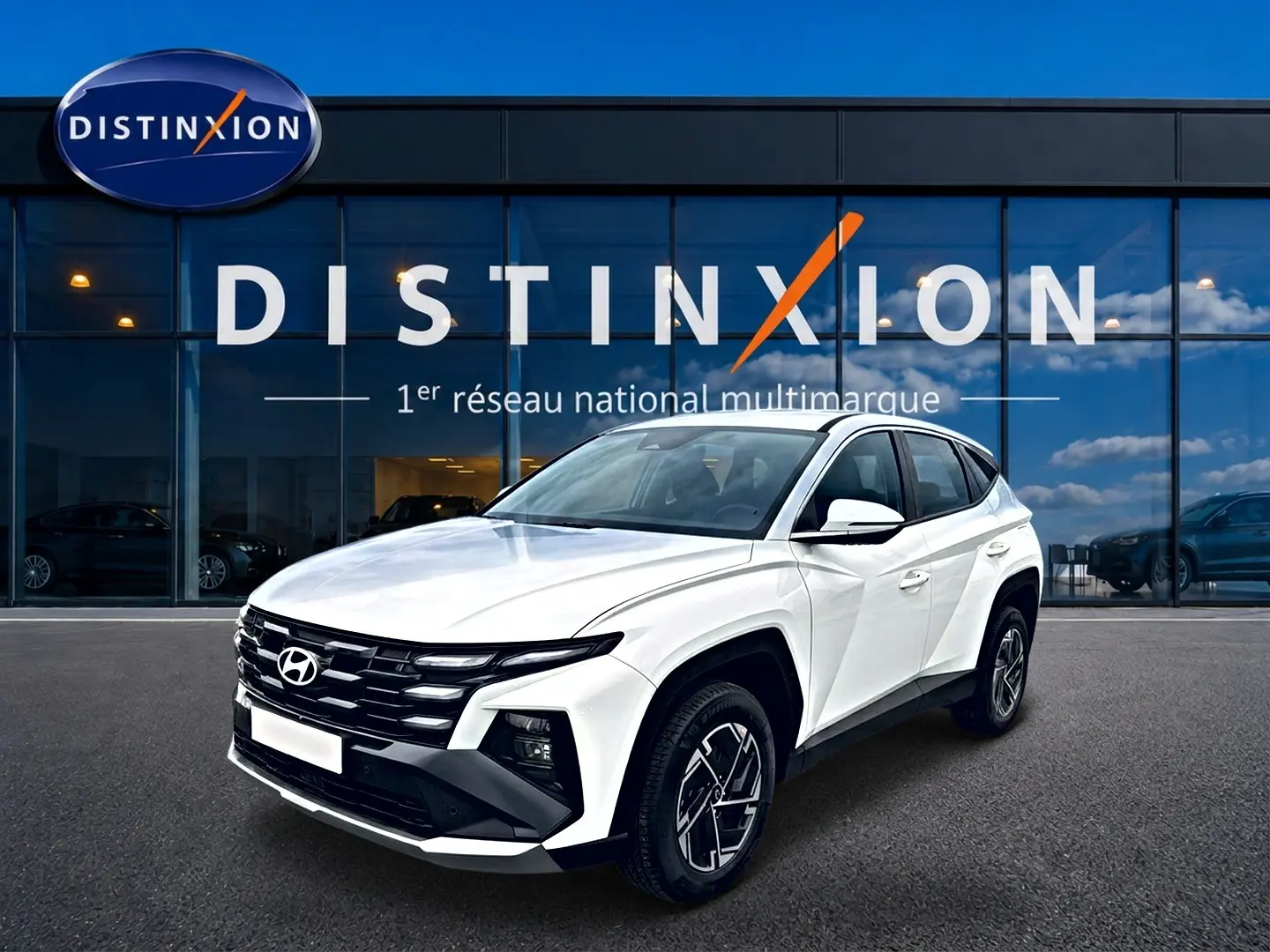 Hyundai Tucson blanc 2026 en 3/4 avant droit, avec calandre noire et jantes alliage 17 pouces visibles.