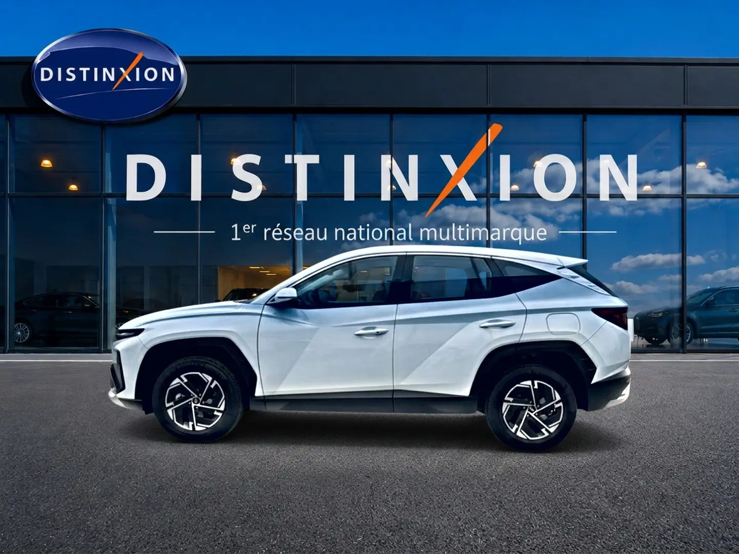 Hyundai Tucson 1.6 t-gdi 239 hybride blanc vu de profil côté gauche devant une vitrine Distinxion.