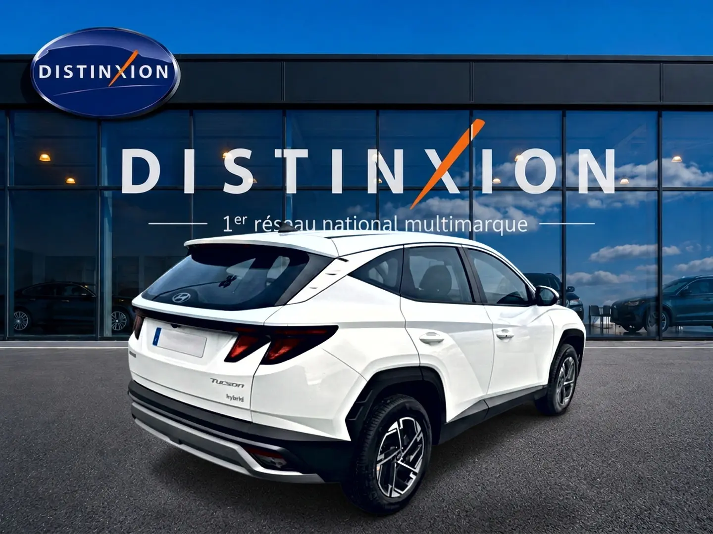 Vue 3/4 arrière droite d'un Hyundai Tucson blanc hybride 2026 avec jantes alliage et feux arrière LED distinctifs.