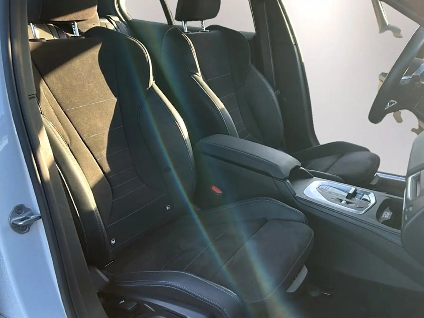Vue intérieure côté conducteur de la BMW Série 1 2025, sièges sport en alcantara noir avec coutures bleues.