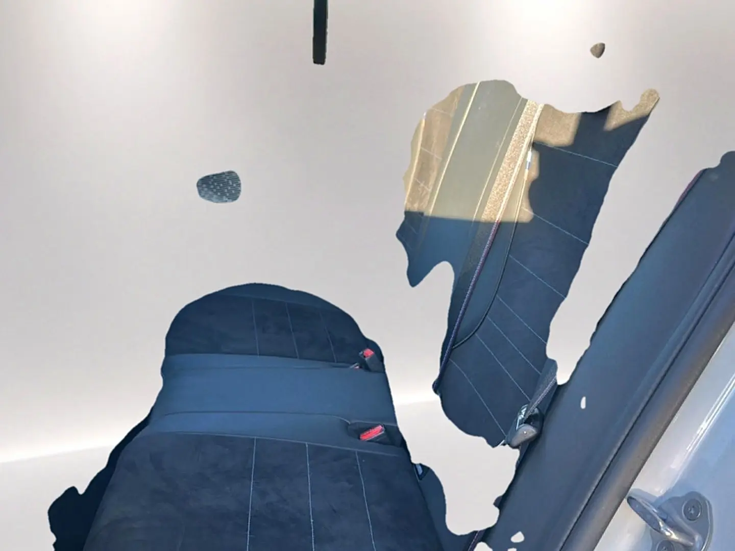 Vue intérieure des sièges arrière en tissu alcantara noir avec coutures bleues d'une BMW Série 1 blanche alpin.