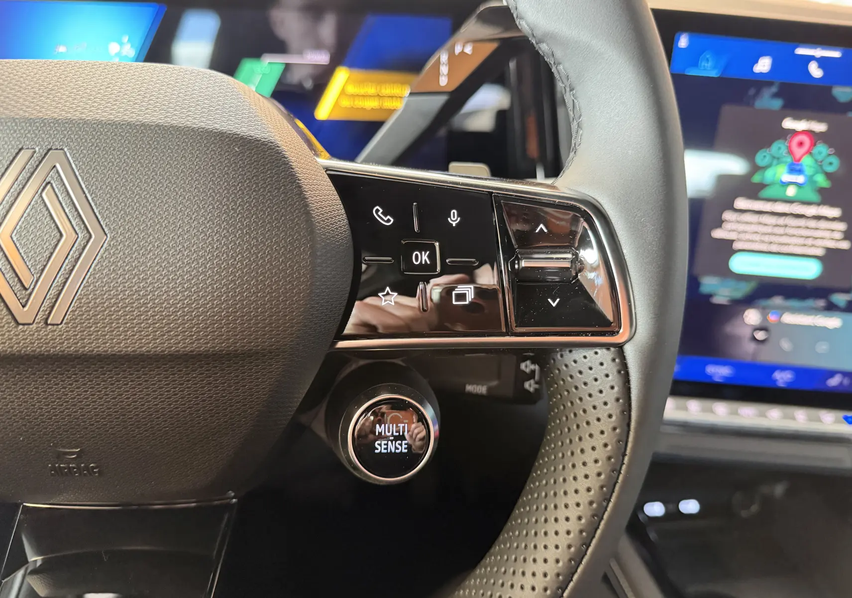 Gros plan sur le volant noir perforé du Renault Austral E-Tech 200, avec commandes tactiles et bouton Multi-Sense visible.