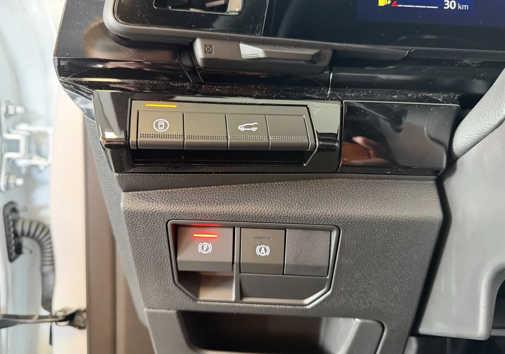 Vue rapprochée des commandes de verrouillage et ouverture du coffre sur le tableau de bord noir du Renault Austral E-Tech.