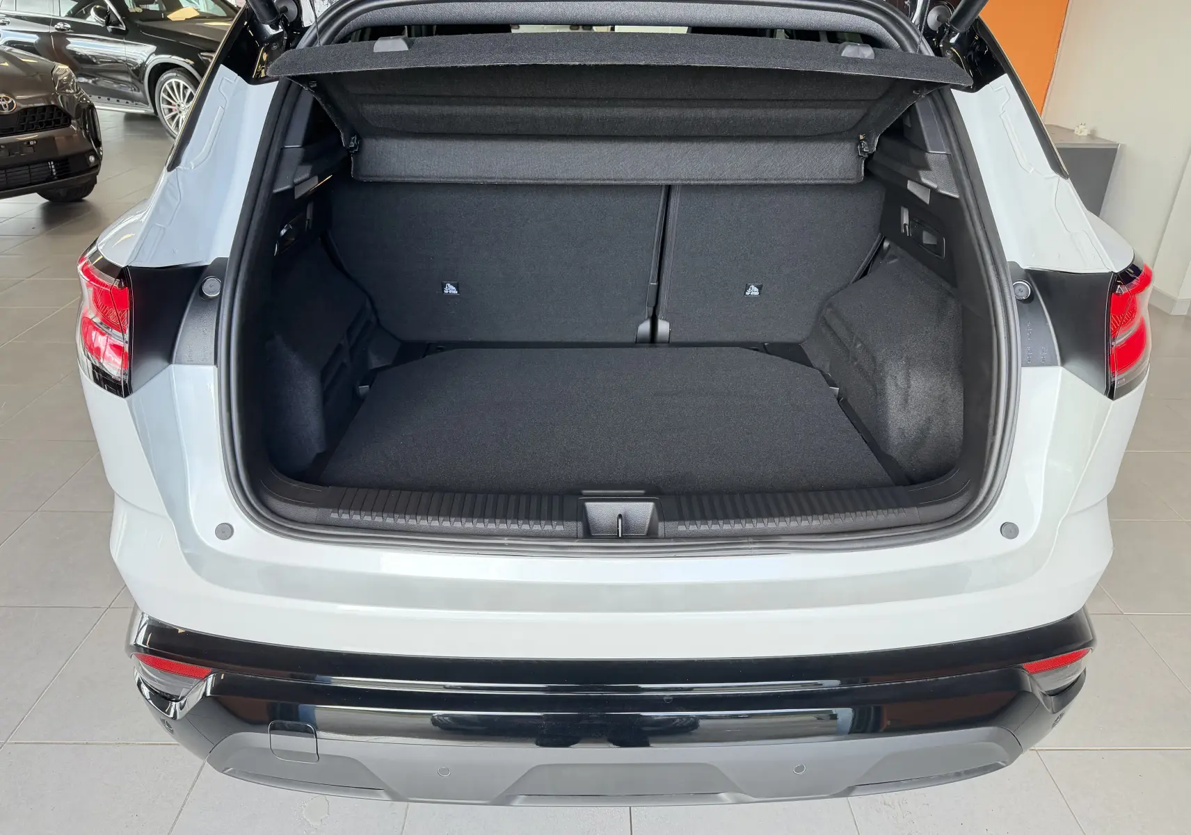 Vue arrière du coffre ouvert d'un Renault Austral E-Tech 200 blanc toit noir, montrant l'espace de chargement vide.