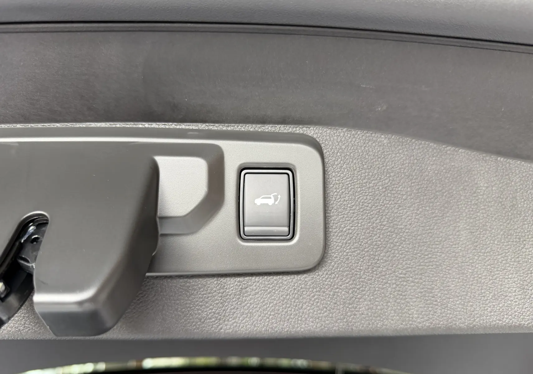 Bouton d'ouverture électrique du coffre sur la garniture intérieure du hayon du Renault Austral blanc toit noir.