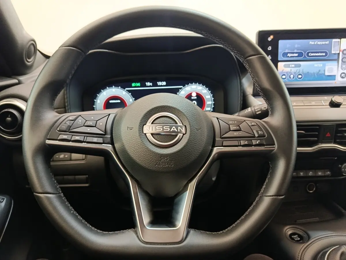 Vue rapprochée du volant noir multifonctions d’un Nissan Juke 2025 avec tableau de bord numérique et écran tactile central.