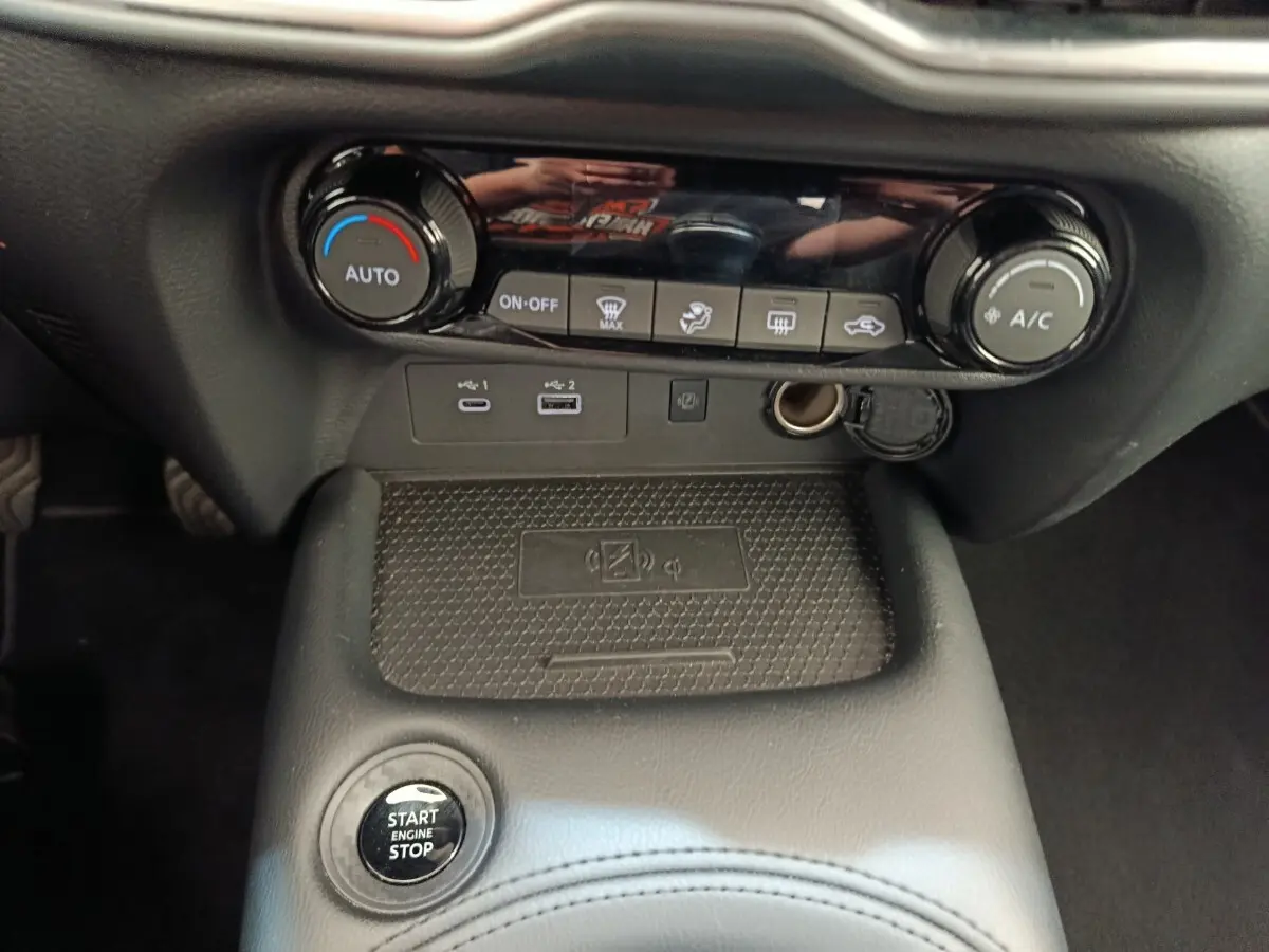 Vue rapprochée de la console centrale noire du Nissan Juke 2025 avec commandes climatisation et ports USB visibles.