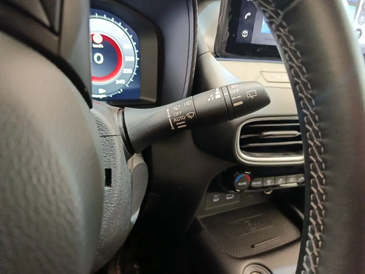 Gros plan sur la manette d'essuie-glace à gauche du volant du Nissan Juke gris clair, tableau de bord partiellement visible.