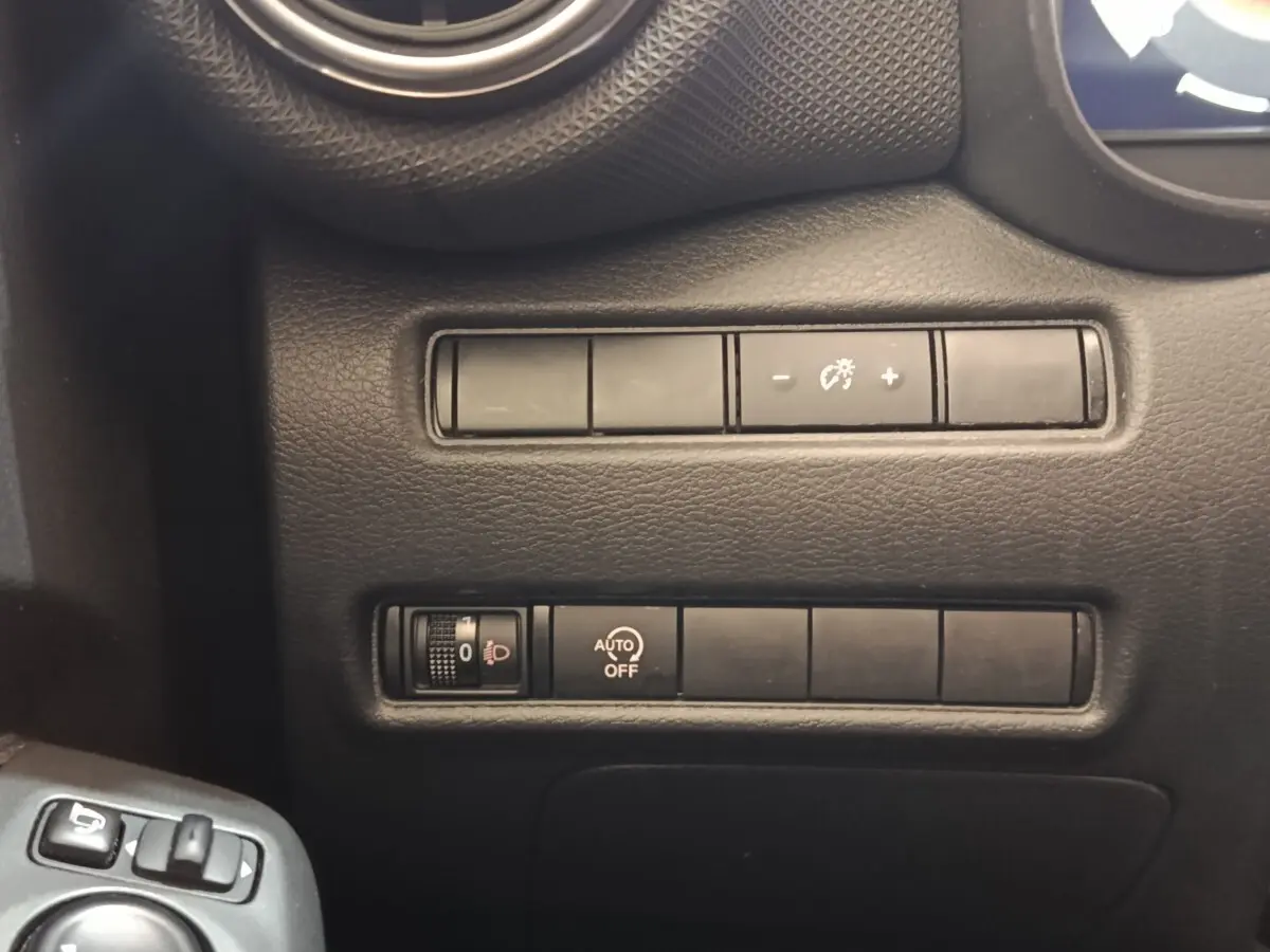 Gros plan sur les commandes de réglage d’éclairage et d’assistance du tableau de bord d’un Nissan Juke gris clair.