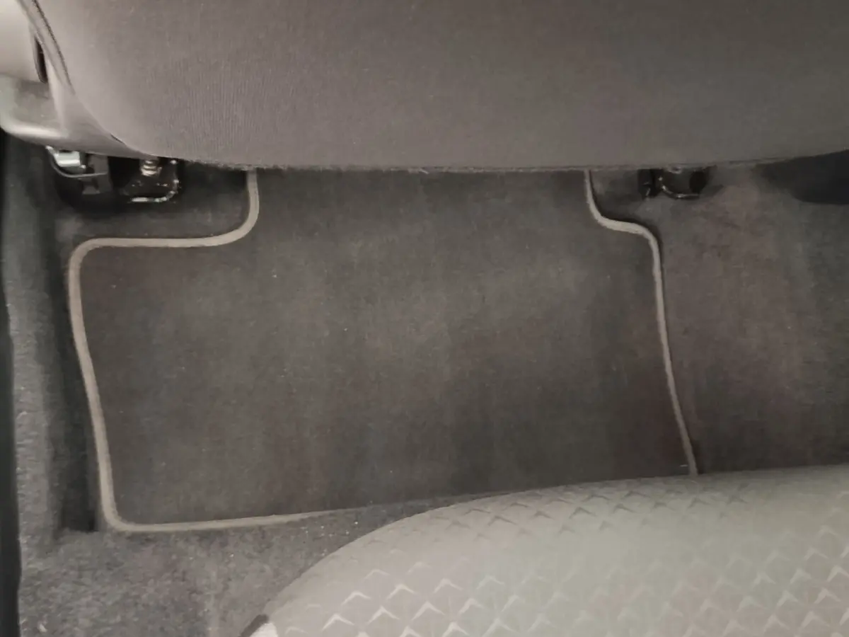 Vue du sol et tapis de sol arrière côté droit du Nissan Juke gris clair 2025, avec partie inférieure du siège visible.