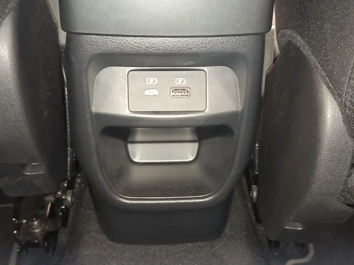 Vue rapprochée de la console centrale arrière du Nissan Juke gris clair, avec prises USB visibles entre les sièges.