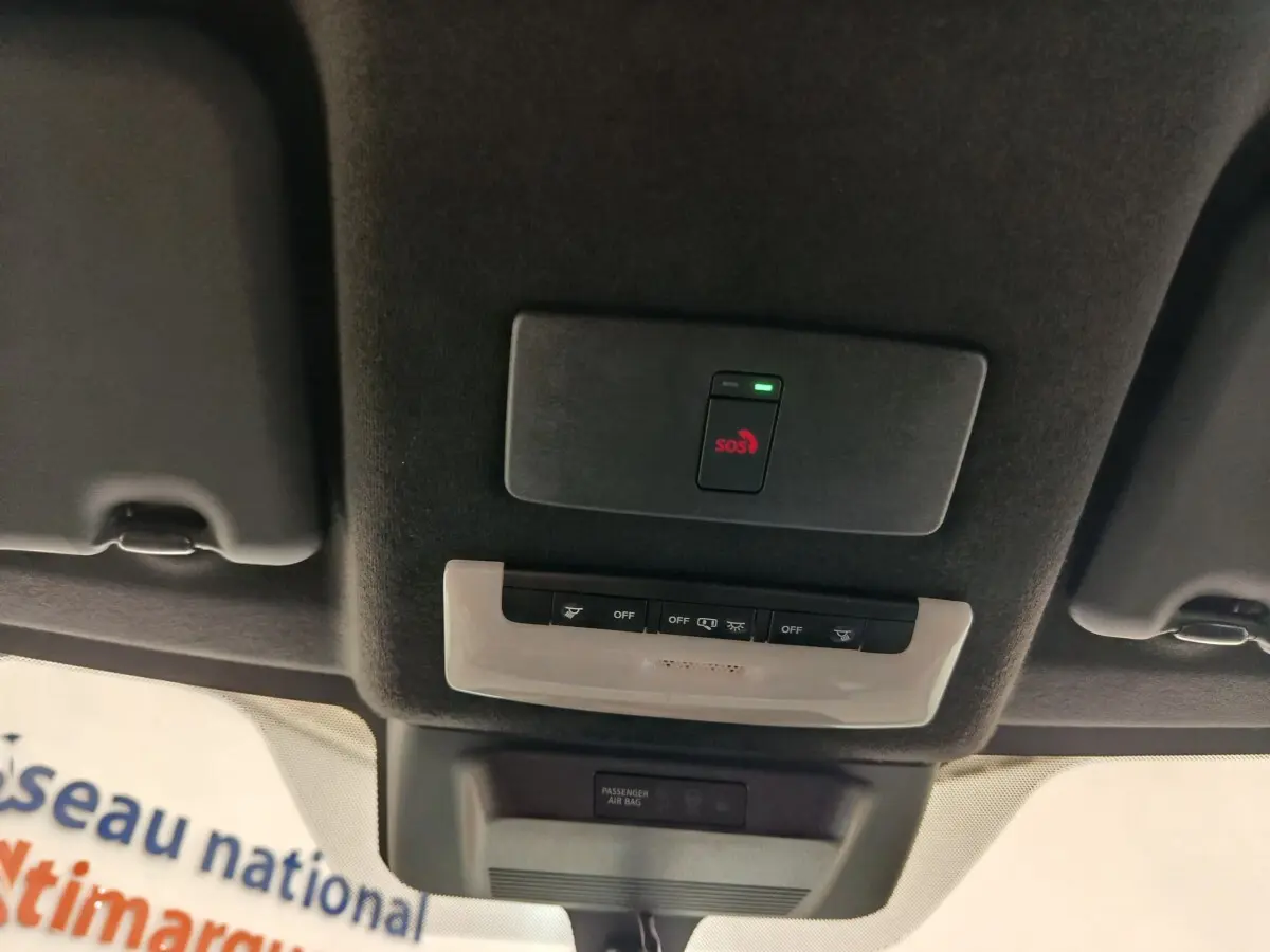Plafonnier intérieur avec bouton SOS rouge et commandes d’éclairage sur le toit d’un Nissan Juke gris clair 2025.