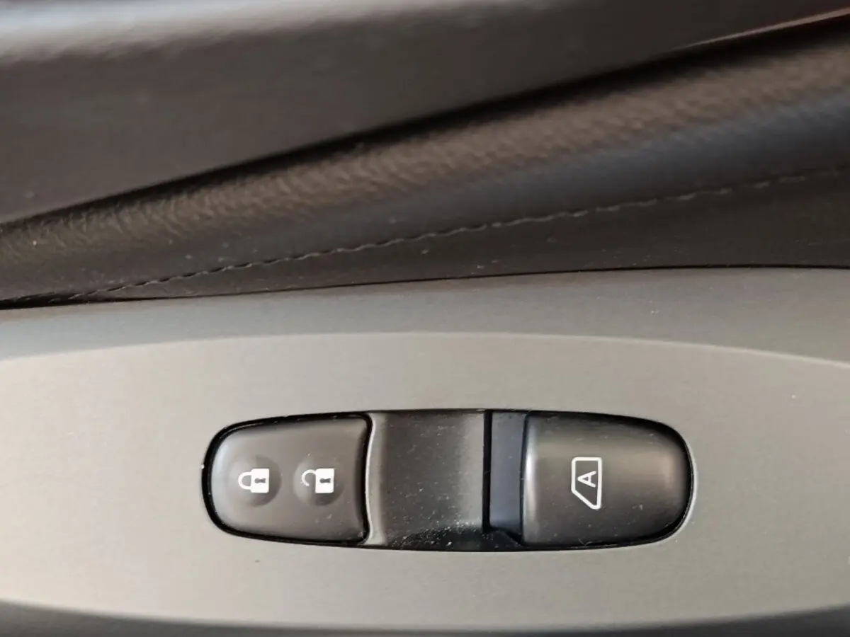Gros plan sur les boutons de verrouillage centralisé et de lève-vitre automatique dans l'habitacle gris clair du Nissan Juke 2025.