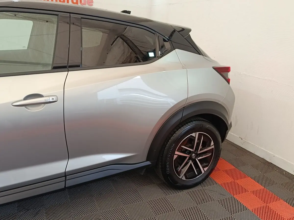 Vue latérale côté droit du Nissan Juke gris clair, mettant en valeur la roue arrière et la ligne de caisse dynamique.