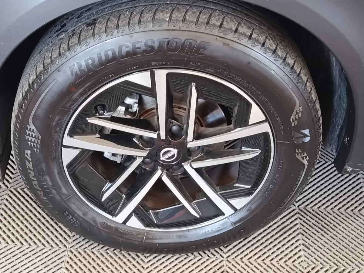 Gros plan sur la roue avant droite du Nissan Juke gris clair avec jante alliage noire et argentée, pneu Bridgestone.