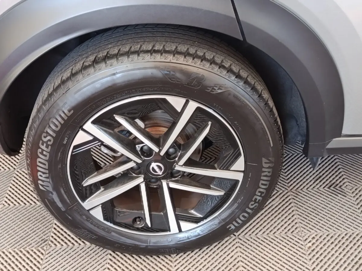 Gros plan sur la roue avant droite gris clair du Nissan Juke 2025 avec jante alliage noire et détails argentés.
