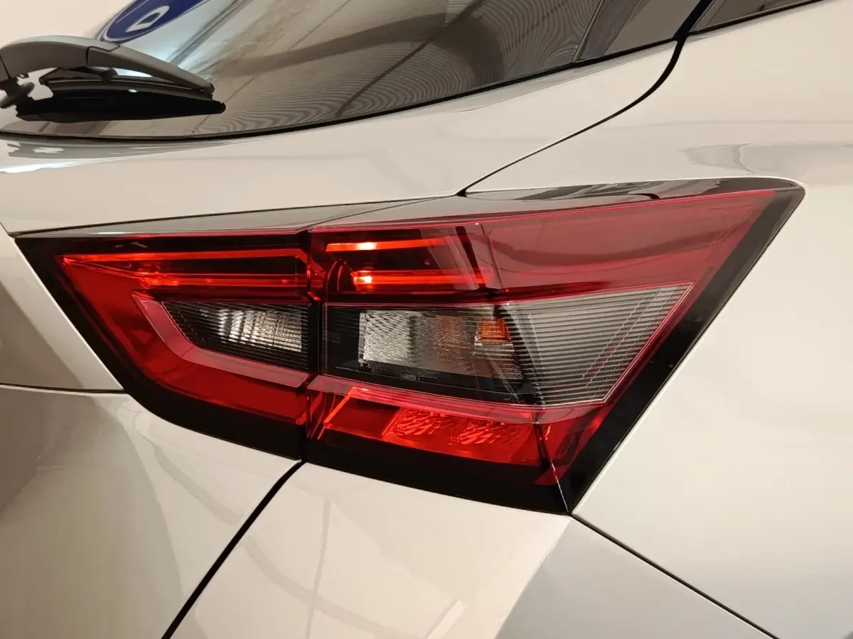 Gros plan sur le feu arrière droit rouge et blanc d’un Nissan Juke gris clair 2025, détails nets et angulaires.