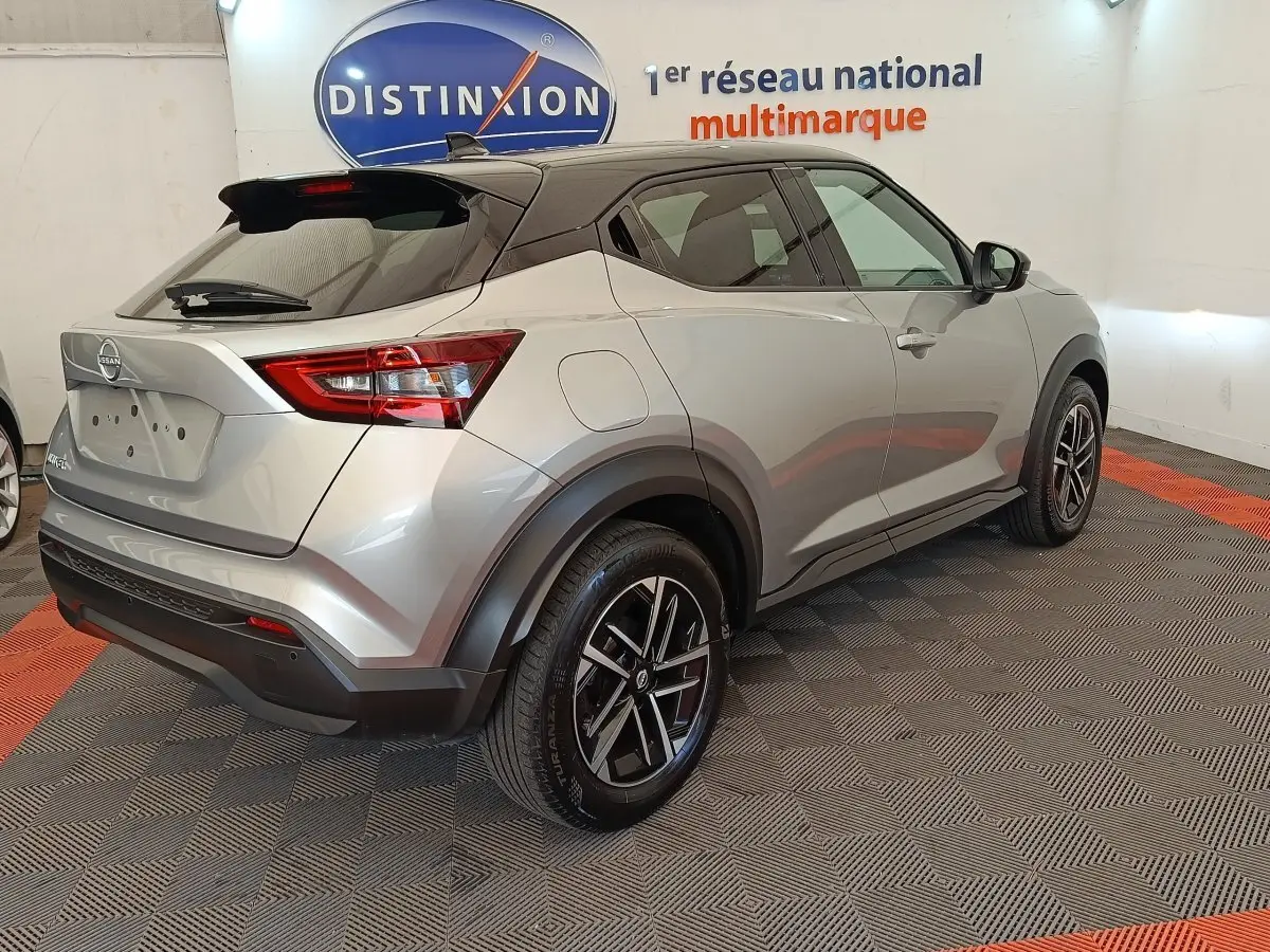 Nissan Juke gris clair vue 3/4 arrière droit, avec jantes alliage noires et toit noir contrasté.